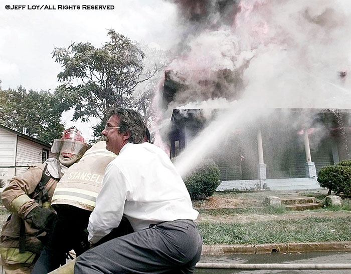 Paris, Texas fire chief Steve Bergin, right, assists firefighters in battling a house fire. The house, which had just been fully restored by its owner, was a complete loss.